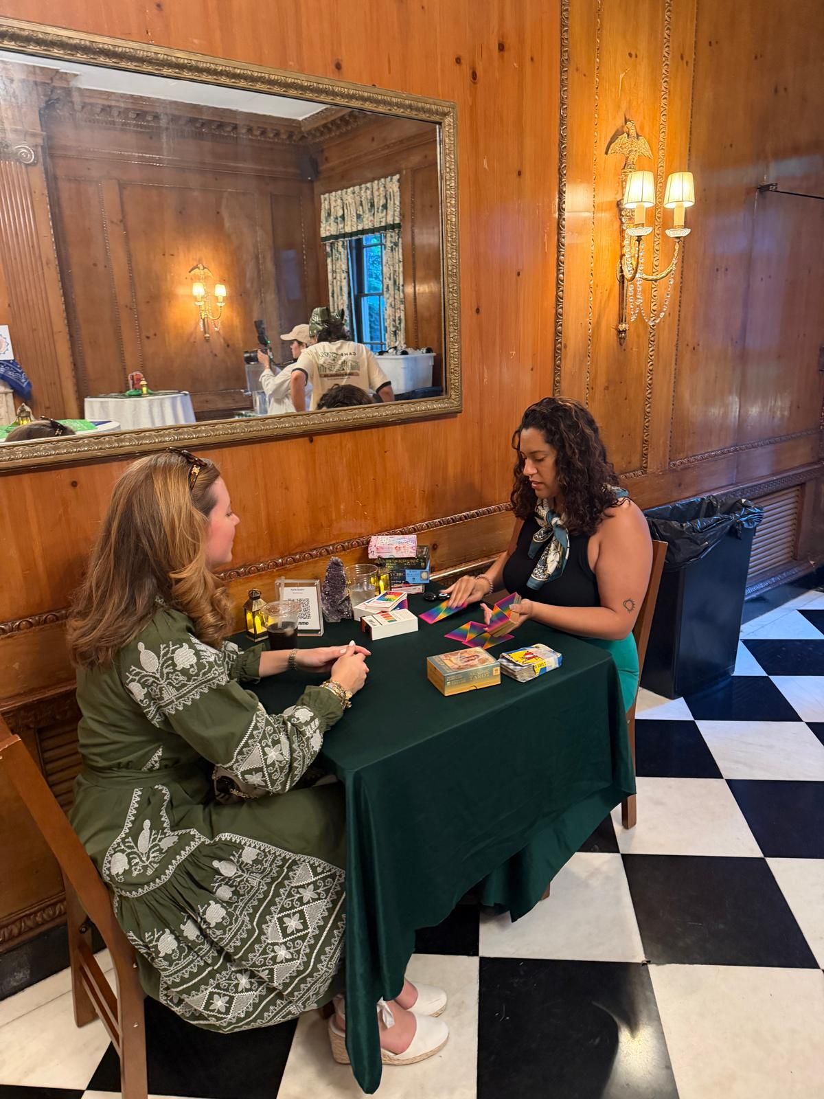 Kaide giving a tarot reading to a guest at a private event in a wood-paneled room