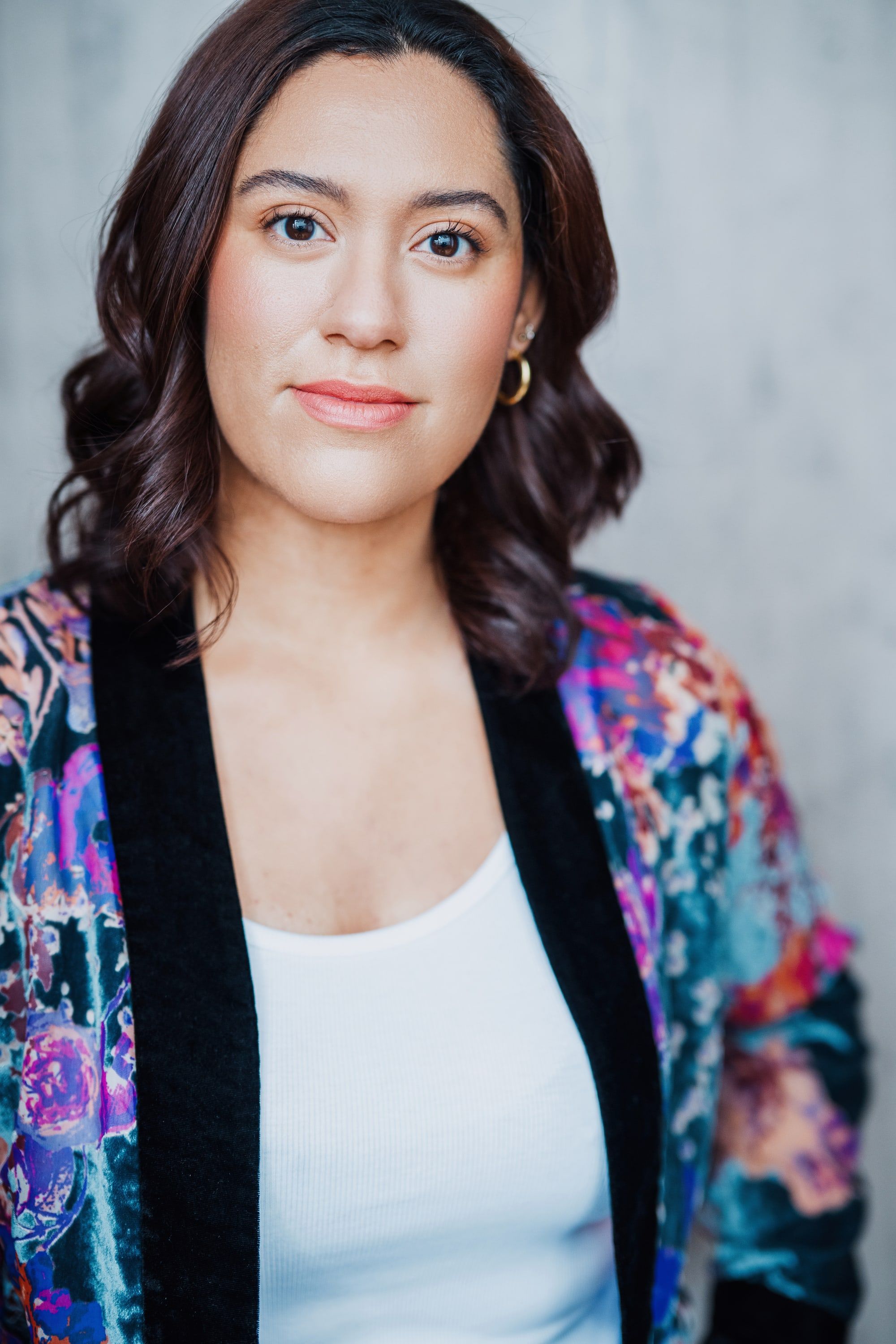 Portrait of Kaide Solano with a soft smile, wearing a colorful floral jacket over a white top